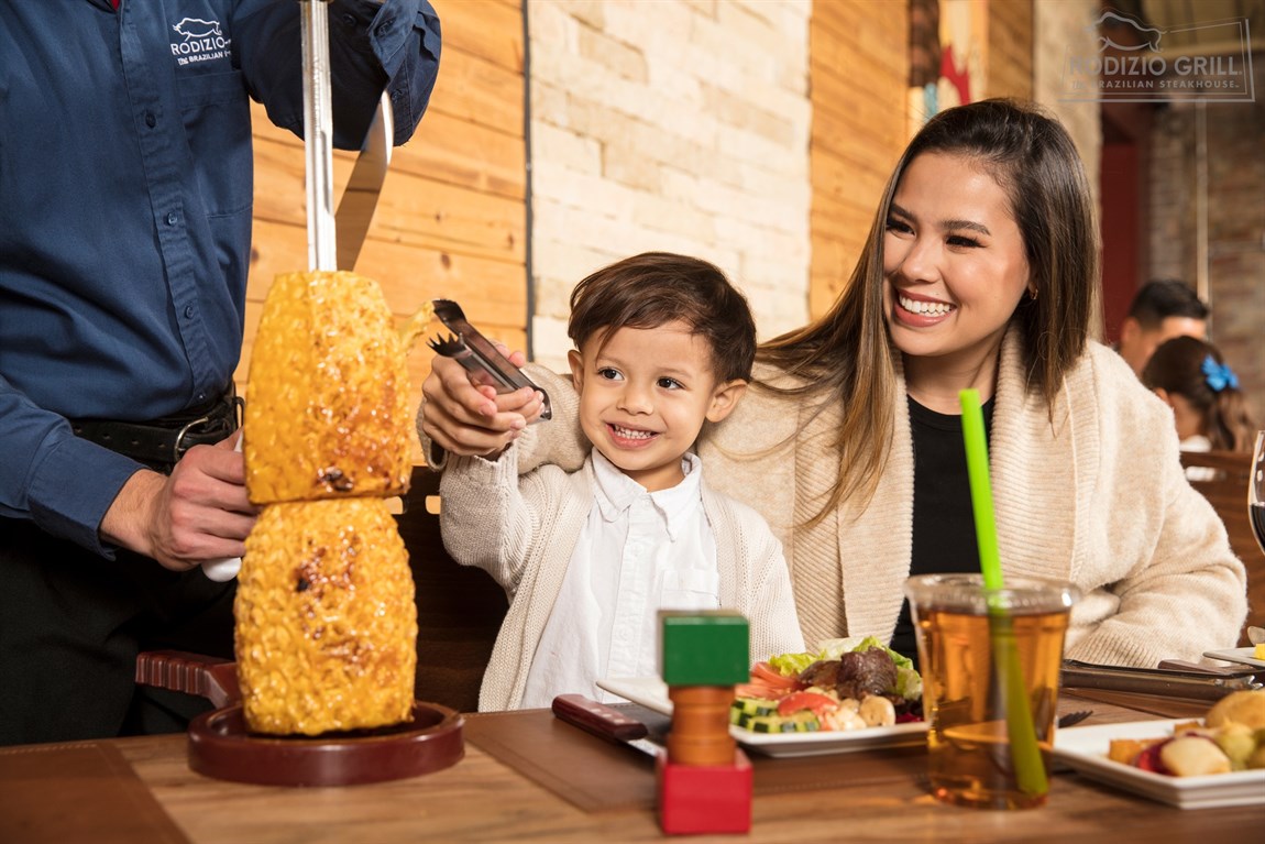 Mother and kids at Rodizio grilled pineapple at the table Photo