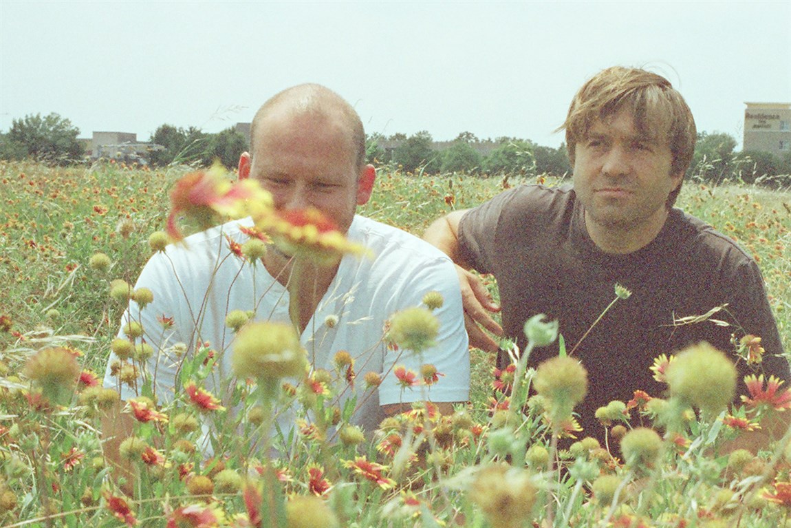 two men sitting a field of wildflowers Photo