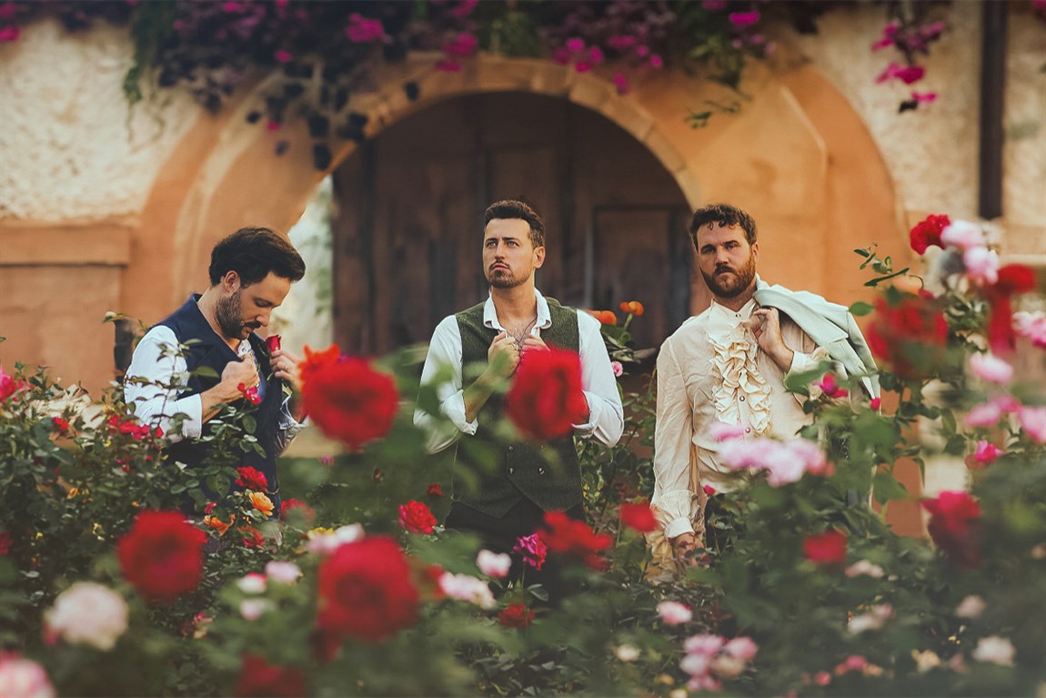 three men standing behind roses Photo