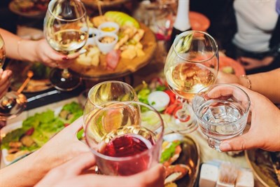 Group of friends gathered around table clinking wine glasses Photo