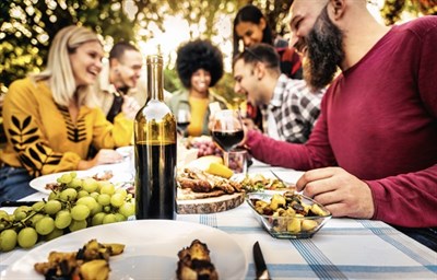 Friends gathered around table enjoying wine and food Photo