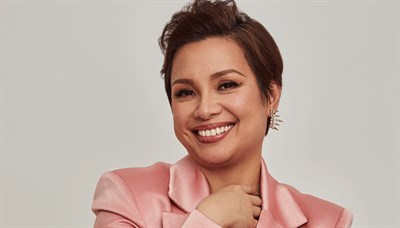 Lea Solanga smiling in a pink blouse. Photo