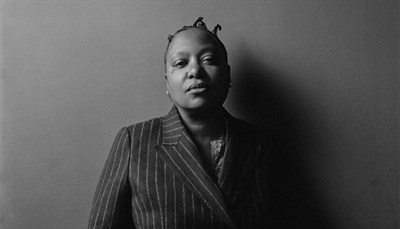 Meshell Ndegeocello black and white portrait in a pinstripe suit. Photo