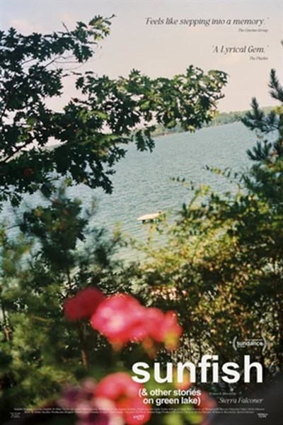 Pink flowers are out of focus in front and green foliage and blue water in focus Photo