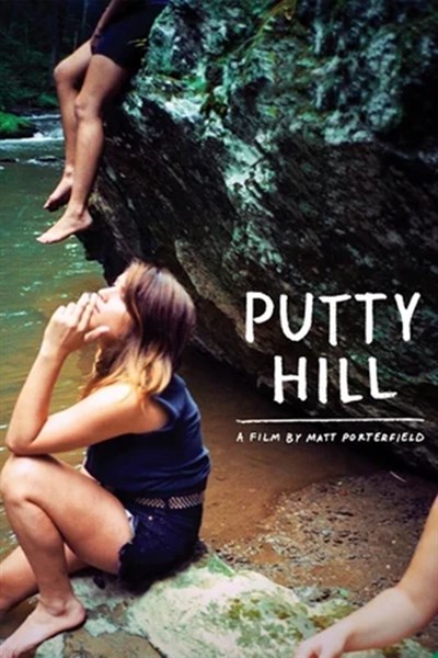 Girl sits on a rock smoking a cigarette, 2 other people are partially visible in the background Photo