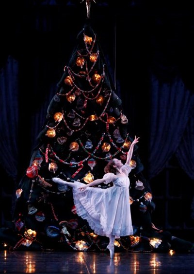 Clara performs an arabesque in front of a Christmas tree Photo