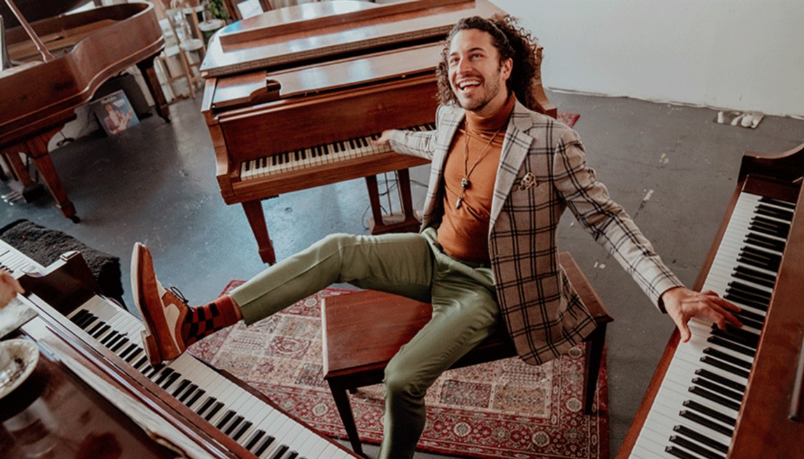 Emnet Cohen sitting on a stool in between three grand pianos Photo