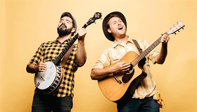 The Okee Dokee Brothers holding their instruments and singing, against a yellow background. Photo