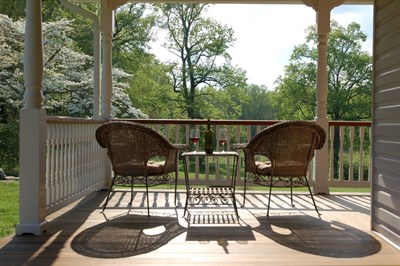 Two chairs and a table with a bottle of wine and two glasses on a porch at the Thanksgiving Farm. Photo