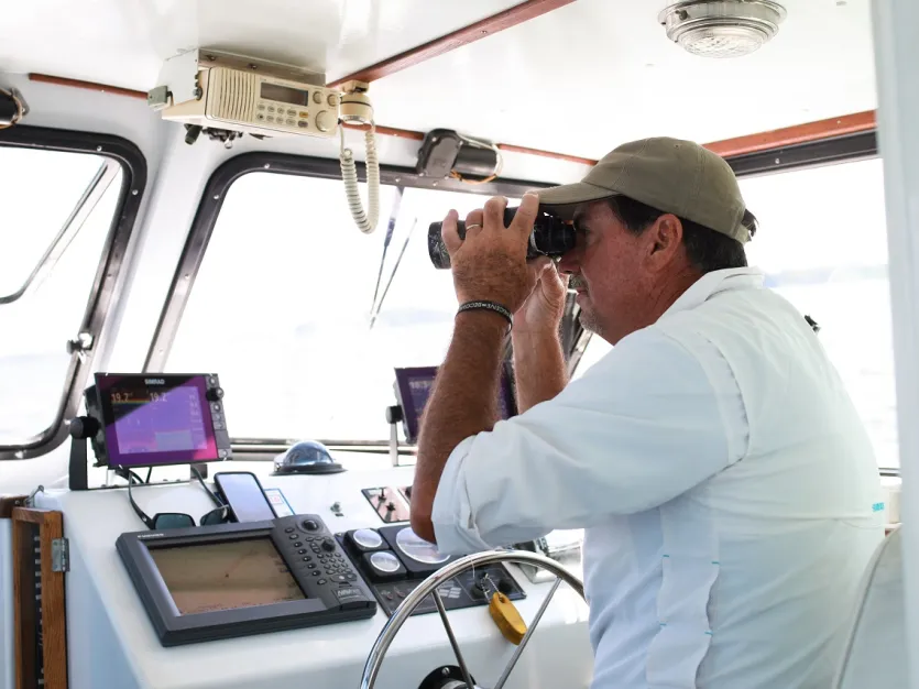 Boat captain looking through binoculars