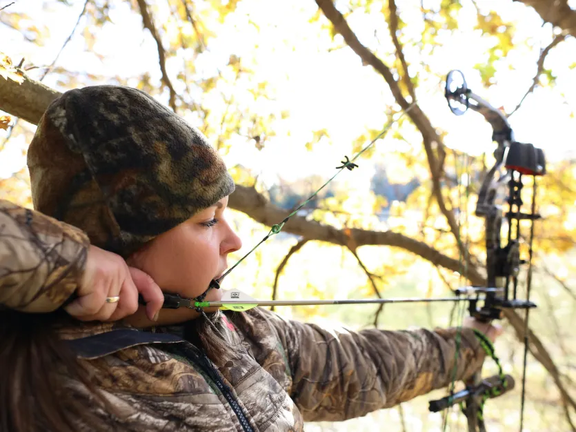 Female archer hunting in full camouflage