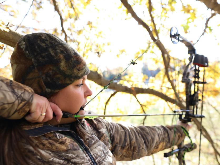 Female archer hunting in full camouflage