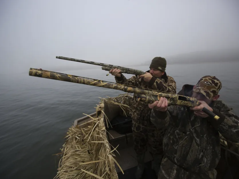 Sportsmen duck hunting from a camouflaged skiff