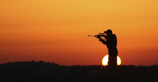 Man firing gun in sunset