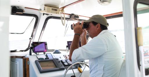 Boat captain looking through binoculars