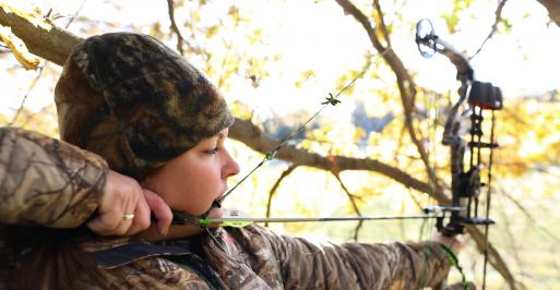 Female archer hunting in full camouflage
