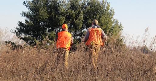 Two hunters walking outside in a field
