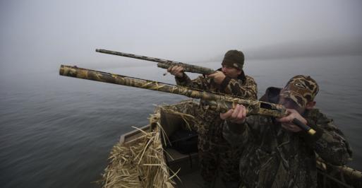 Sportsmen duck hunting from a camouflaged skiff