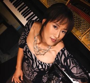 Vienna Teng leaning on piano Photo