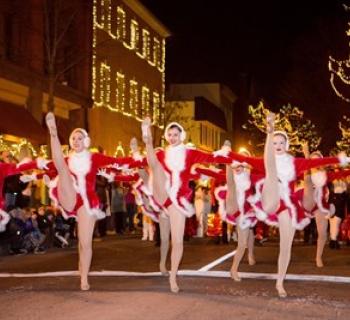 Dancers participating in the procession. The street is twinkling with holiday lights Photo