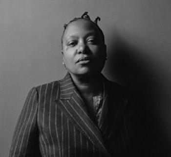 Meshell Ndegeocello black and white portrait in a pinstripe suit. Photo