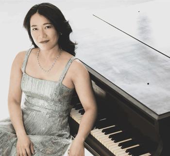 Charlotte Hu leaning on a piano Photo