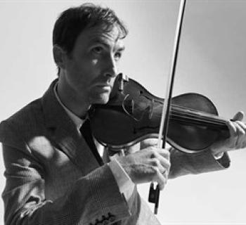 Black and white portrait of Andrew Bird playing the violin. Photo