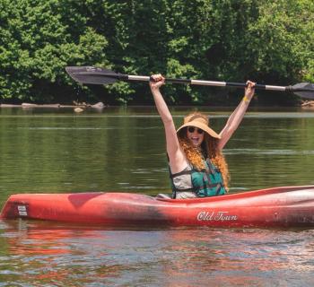 Person in kayak with an excited look on her face.  Photo