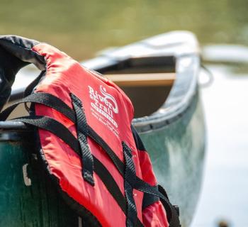 Picture of a Personal Floatation Device hanging on a canoe.  Photo