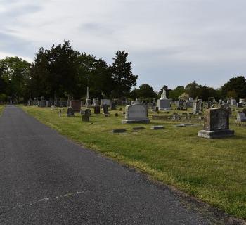 View of Parsons Cemetery with paved road going through and gravestones to the right. Photo