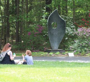 a mother and child having a picnic in front of a large sculpture Photo