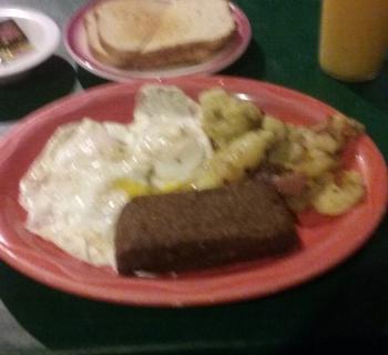 Fried eggs, scrappple, home fried potatoes, toast and juice. Photo