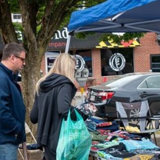 People searching through old clothing and miscellanea on a table outside Photo