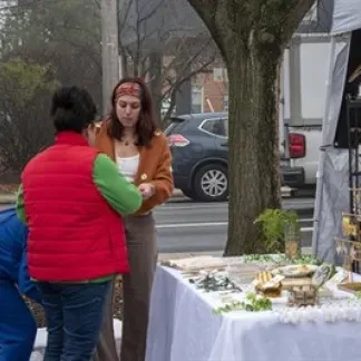 A woman talks with another woman about jewelry for sale at an outdoor booth. Photo