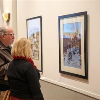 Two people observing the winning artwork at the 2023 Holiday Art Competition. Photo