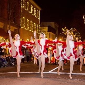 Dancers participating in the procession. The street is twinkling with holiday lights Photo