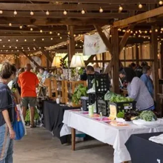 Image of shoppers and vendors in our historic tobacco barn during a market. Photo