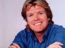 Peter Noone wearing a blue shirt and smiling Photo