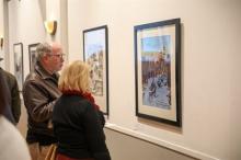 Two people observing the winning artwork at the 2023 Holiday Art Competition. Photo