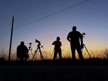 A group of amateur astronomers look at the night sky in profile.  Photo