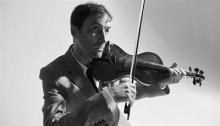 Black and white portrait of Andrew Bird playing the violin. Photo