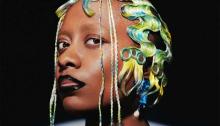 Portrait of Cécile McLorin Salvant with blue and yellow hair, with a black background. Photo