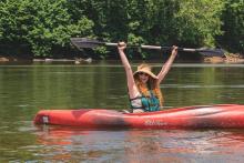 Person in kayak with an excited look on her face.  Photo