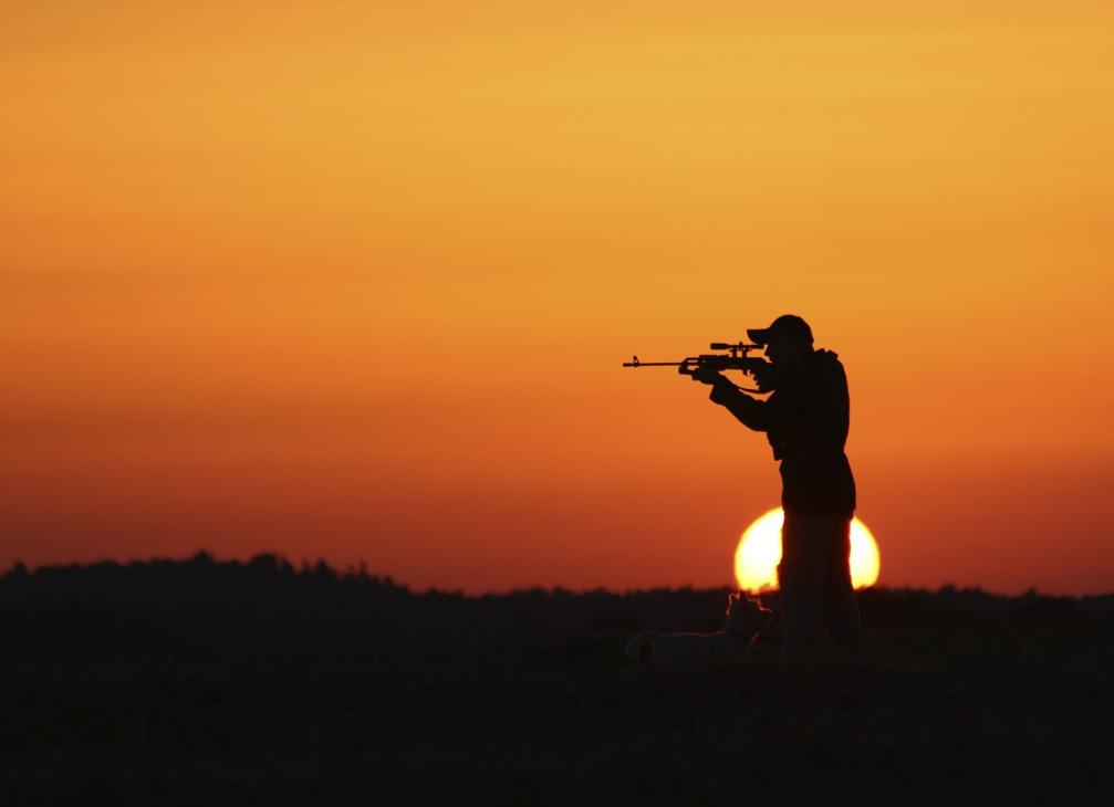 Man firing gun in sunset